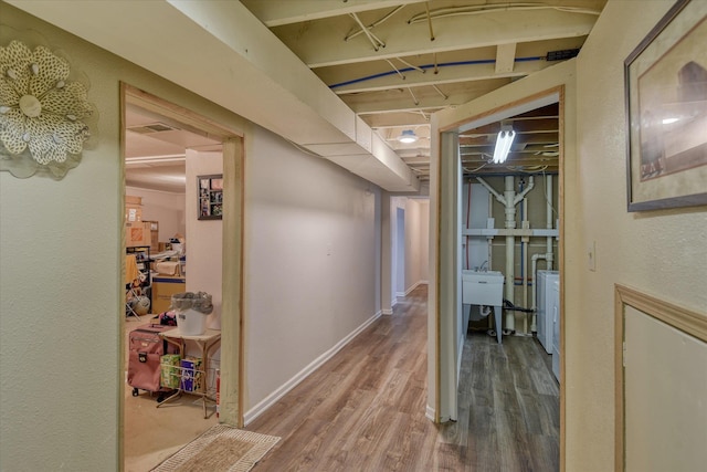 corridor featuring visible vents, baseboards, separate washer and dryer, and wood finished floors