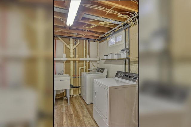 clothes washing area featuring washer and dryer, laundry area, light wood-type flooring, and a sink