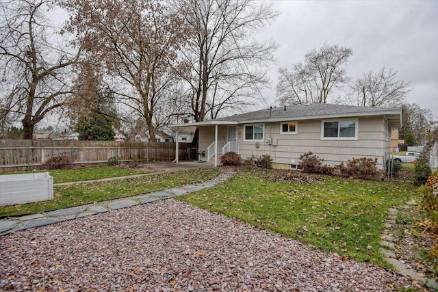 rear view of property with a gate, a lawn, and fence