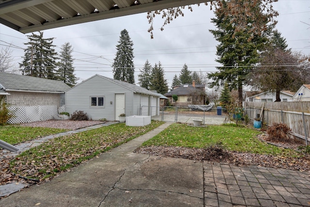 view of yard with a garage, fence, an outdoor structure, and a gate