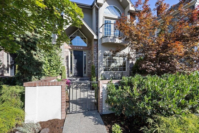 view of front facade with stucco siding, a fenced front yard, and a gate