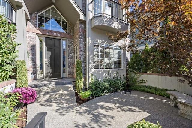 view of exterior entry with stucco siding and fence