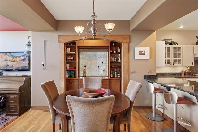 dining room with baseboards, an inviting chandelier, and light wood-style flooring