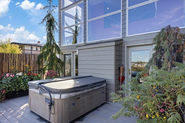 exterior space with fence, a deck, and a hot tub