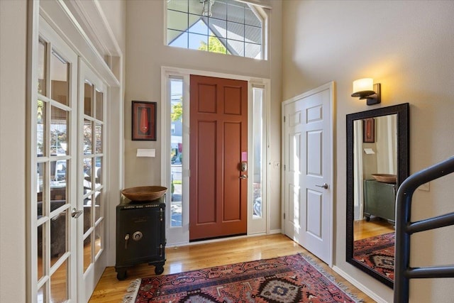 entrance foyer featuring light wood-type flooring, a high ceiling, and french doors