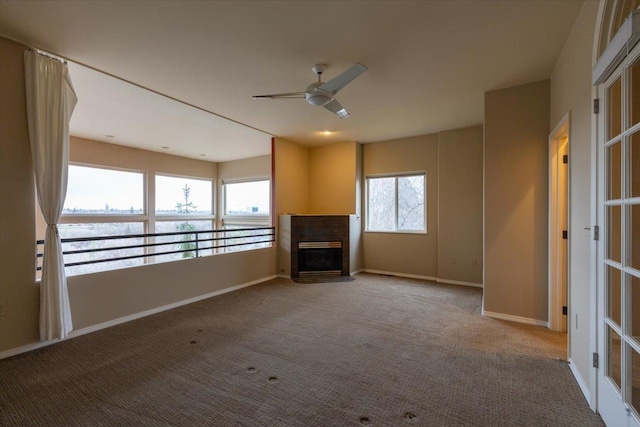 unfurnished living room featuring a fireplace with flush hearth, plenty of natural light, a ceiling fan, and carpet