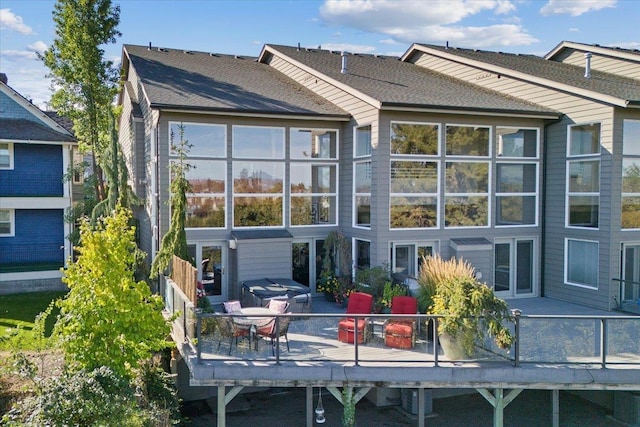 rear view of house with a deck and roof with shingles