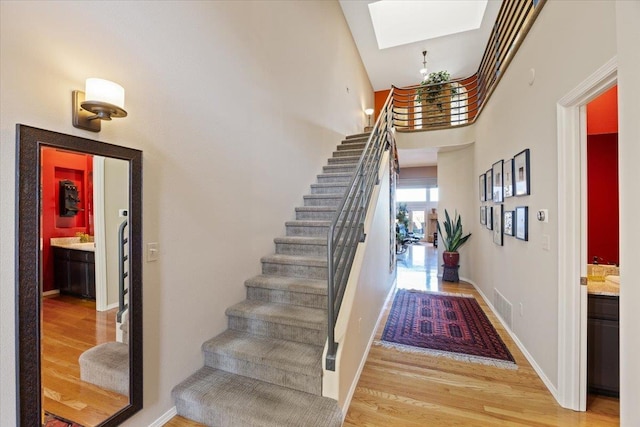 stairs featuring visible vents, a skylight, baseboards, and wood finished floors