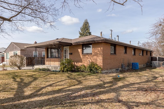 exterior space with brick siding, a yard, and fence