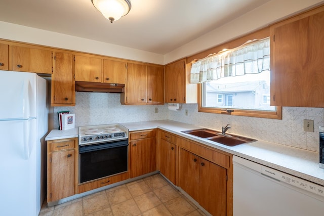 kitchen with under cabinet range hood, white appliances, light countertops, and a sink