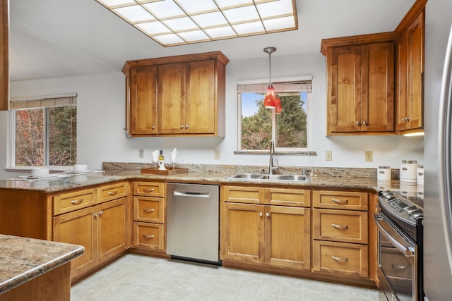 kitchen featuring a peninsula, a sink, stainless steel appliances, pendant lighting, and brown cabinets