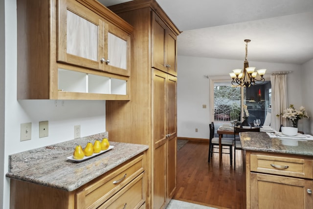 kitchen featuring a notable chandelier, decorative light fixtures, light stone counters, wood finished floors, and vaulted ceiling