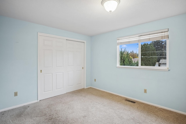 unfurnished bedroom with visible vents, carpet floors, baseboards, and a closet