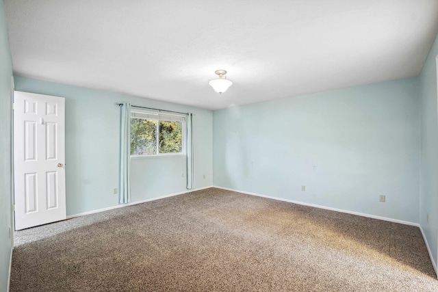 spare room with baseboards and carpet floors