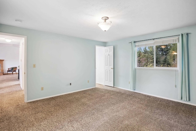 empty room with visible vents, carpet, and baseboards