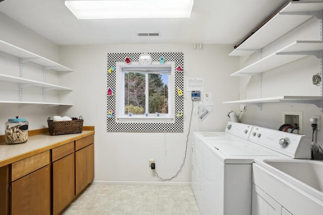 washroom with visible vents, baseboards, washing machine and dryer, cabinet space, and a sink