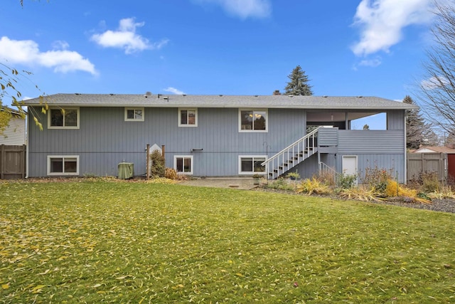 rear view of property with a lawn, stairs, and fence