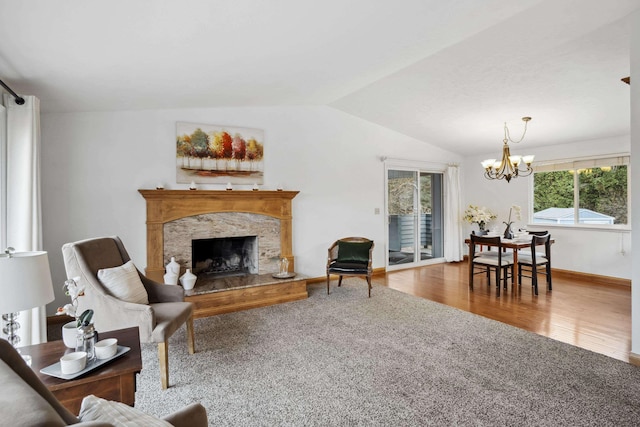 living area featuring a notable chandelier, wood finished floors, a premium fireplace, baseboards, and vaulted ceiling