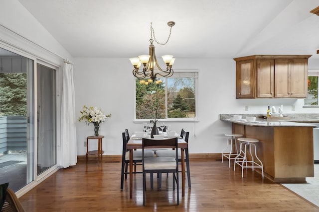 dining space featuring baseboards, wood finished floors, a chandelier, and vaulted ceiling