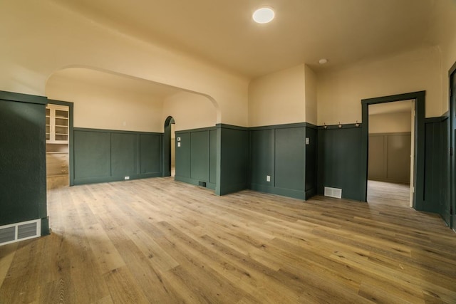 spare room with a wainscoted wall, visible vents, and wood finished floors