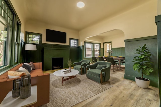 living area with wainscoting, a fireplace, and wood finished floors