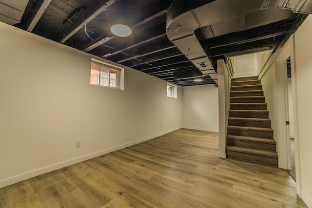 basement featuring stairway, baseboards, visible vents, and wood finished floors