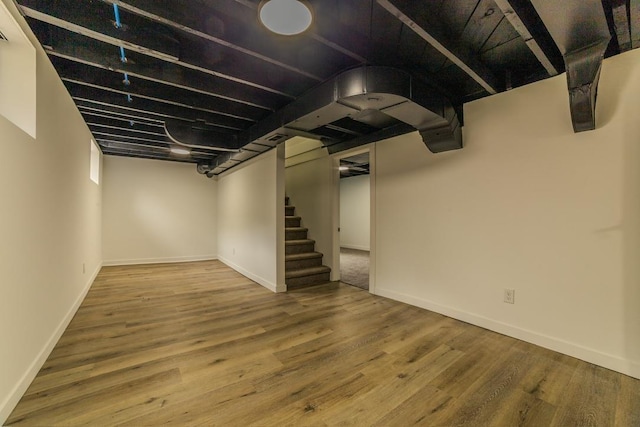 finished below grade area featuring baseboards, wood finished floors, and stairs