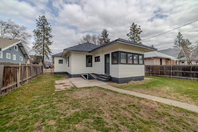 back of property with a yard, a fenced backyard, and entry steps