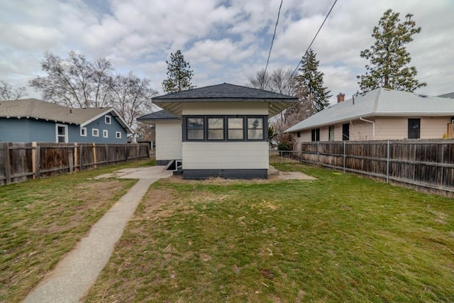 rear view of house with a lawn and a fenced backyard