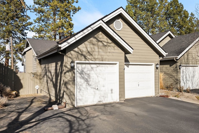 garage featuring aphalt driveway and fence