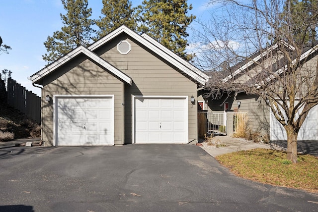 garage featuring driveway and fence