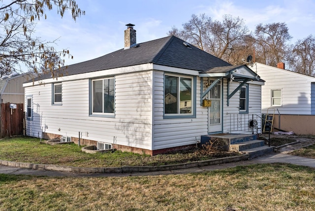 rear view of property featuring a yard, a shingled roof, a chimney, and fence