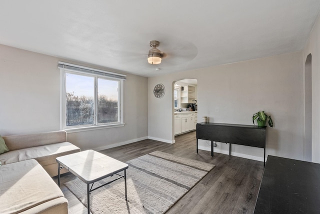 living area featuring baseboards, arched walkways, and wood finished floors