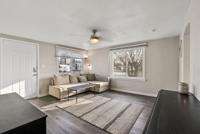 living area with baseboards, wood finished floors, and a ceiling fan