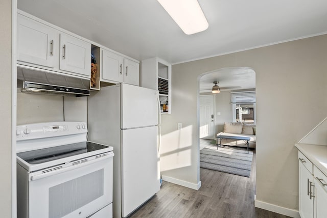 kitchen with under cabinet range hood, wood finished floors, arched walkways, white cabinets, and white appliances