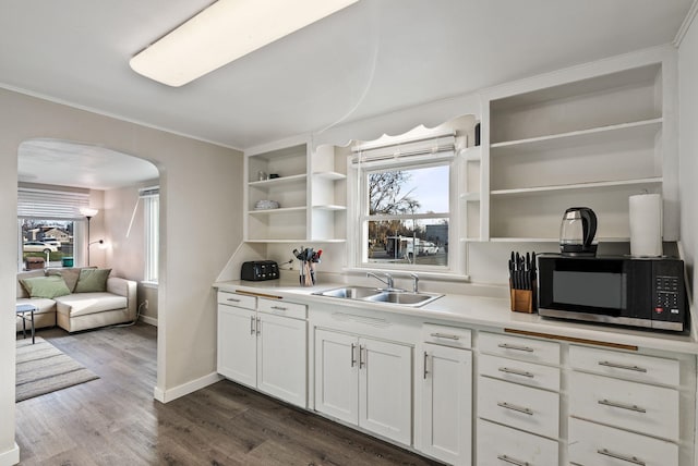 kitchen with open shelves, arched walkways, a wealth of natural light, and a sink