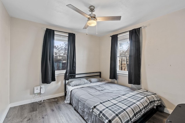 bedroom featuring ceiling fan, baseboards, and wood finished floors