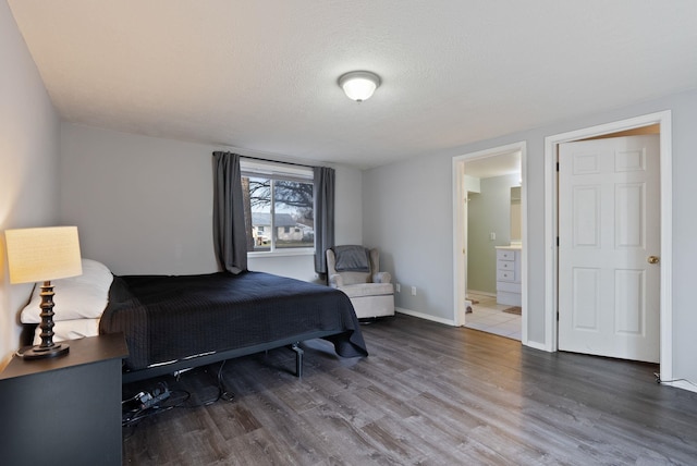 bedroom featuring baseboards, a textured ceiling, ensuite bath, and wood finished floors