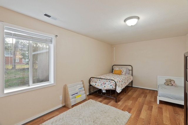 bedroom featuring wood finished floors, visible vents, and baseboards