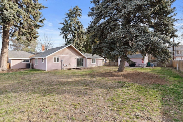 back of property featuring a lawn and fence