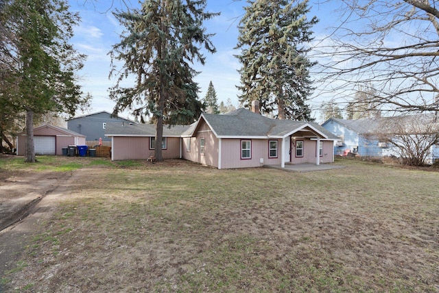 rear view of house with a lawn, driveway, and a patio area