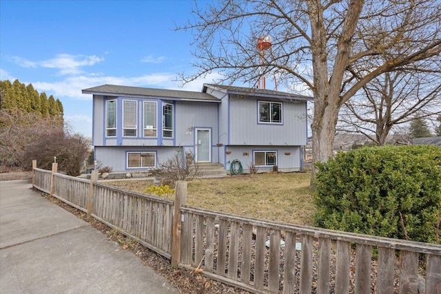 raised ranch with a fenced front yard and a front yard