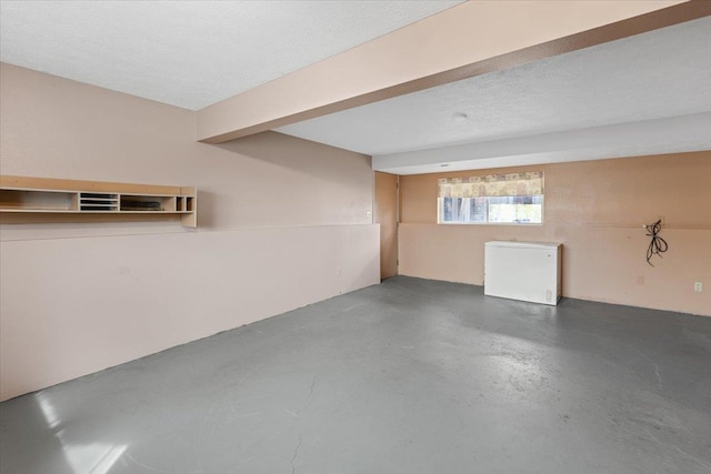 basement featuring fridge and a textured ceiling