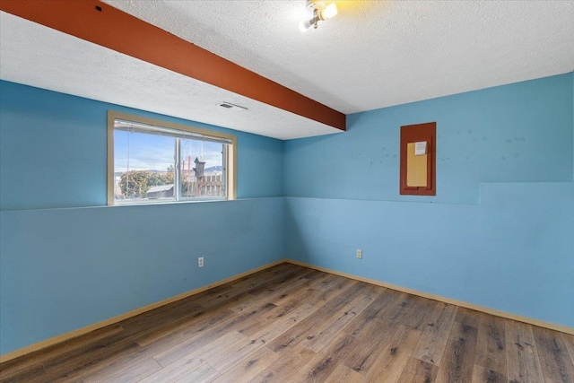 unfurnished room with visible vents, a textured ceiling, baseboards, and wood finished floors