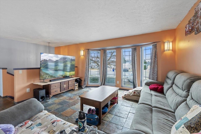 living room with a textured ceiling, baseboards, and stone tile flooring