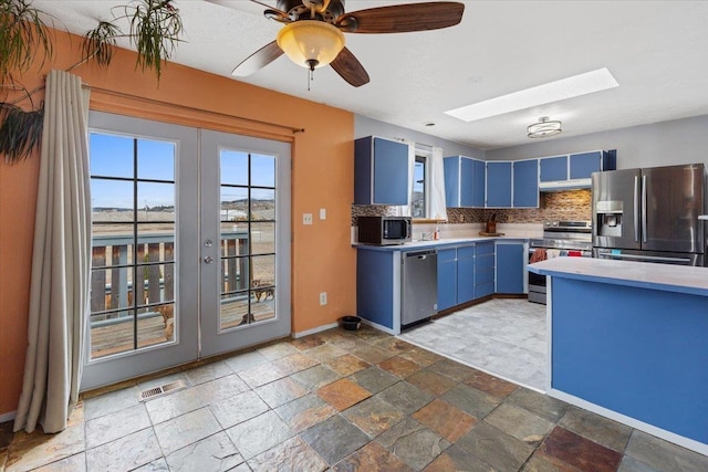 kitchen with blue cabinets, visible vents, stainless steel appliances, a skylight, and decorative backsplash