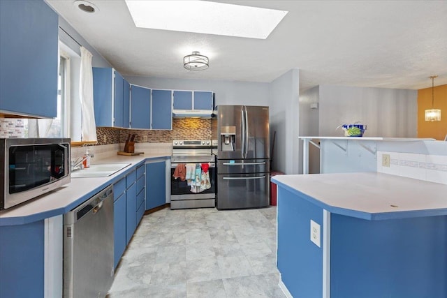 kitchen with blue cabinets, appliances with stainless steel finishes, under cabinet range hood, and a sink