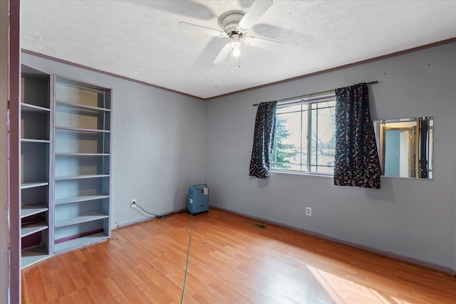 spare room featuring ornamental molding, a textured ceiling, and wood finished floors