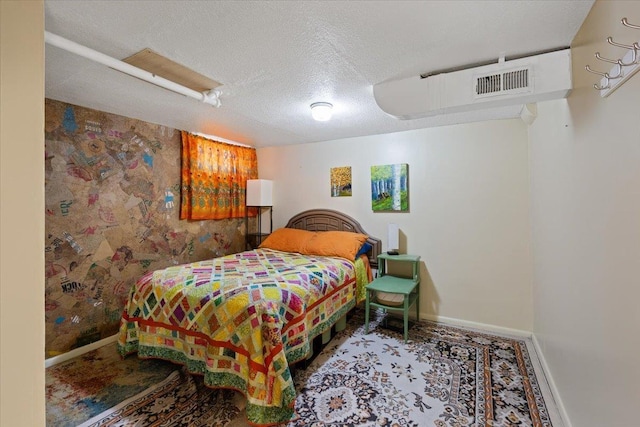 bedroom featuring baseboards, visible vents, and a textured ceiling