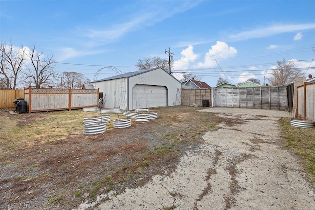 view of yard featuring a detached garage, an outbuilding, central AC, and fence